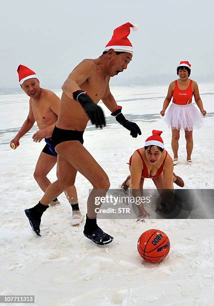 Group of elderly Chinese residents wearing Santa hats play football on a frozen river, as they gather for a winter swim in Shenyang, northeastern...