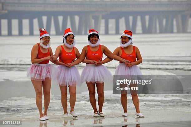 Group of elderly Chinese women gather to pose in 'Santarina' costumes on a frozen river as they prepare for a dip in the icy waters, in Shenyang,...