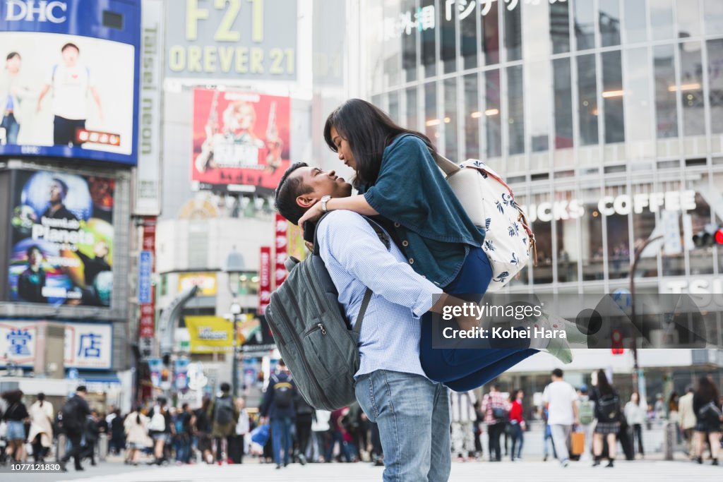 Asian couple on a trip embracing at Shibuya crossing