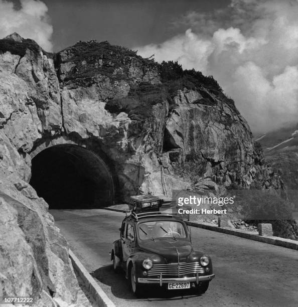 Car with baggage on the roof rack exits the newly built Susten Pass tunnel in the Swiss Alps which links Innertkirchen and Wassen in Switzerland. The...