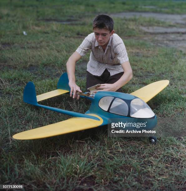 Boy playing with a twin-boom model aircraft, circa 1960.