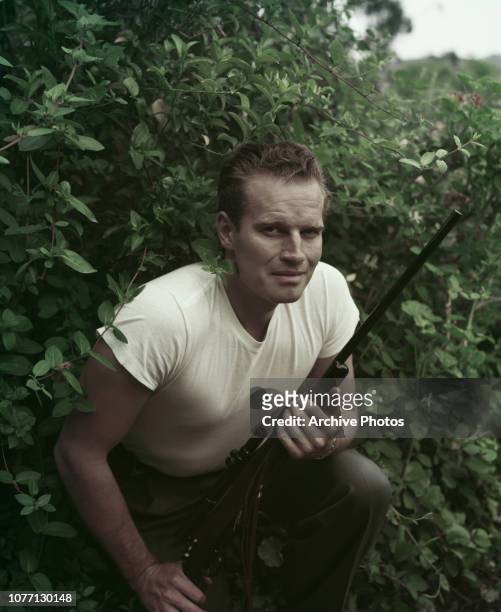American actor Charlton Heston holding a rifle, circa 1955.