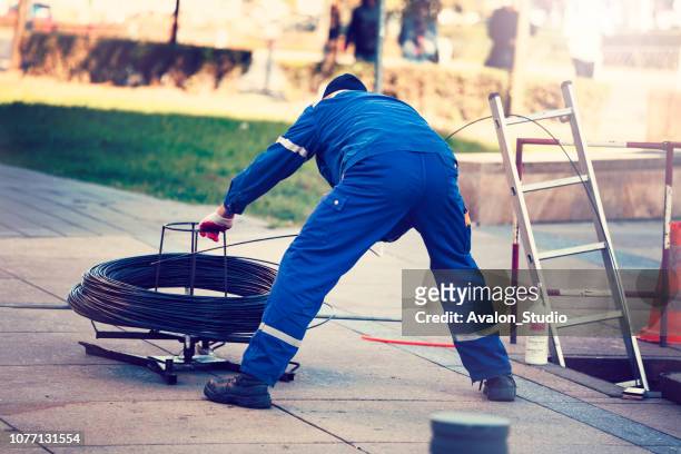 worker pulls the fiber optic cable - cable installation stock pictures, royalty-free photos & images