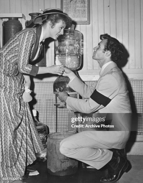 American actor James Mitchell helps co-star Amanda Blake to a cup of Magnetic Spring Water on the set of the film 'Stars In My Crown', 1950.