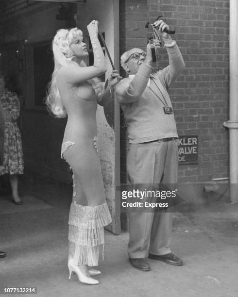 American actress Jayne Mansfield in costume for the film 'Too Hot To Handle', aka 'Playgirl After Dark', 16th September 1959. She is examining film...