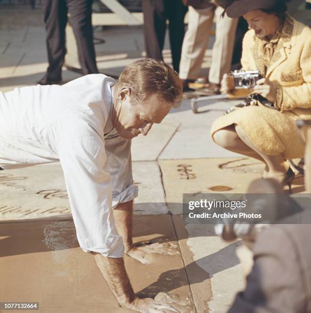 American actor Charlton Heston plants his handprints in cement outside Grauman's Chinese Theatre, Hollywood, California, 18th January 1962. He is...