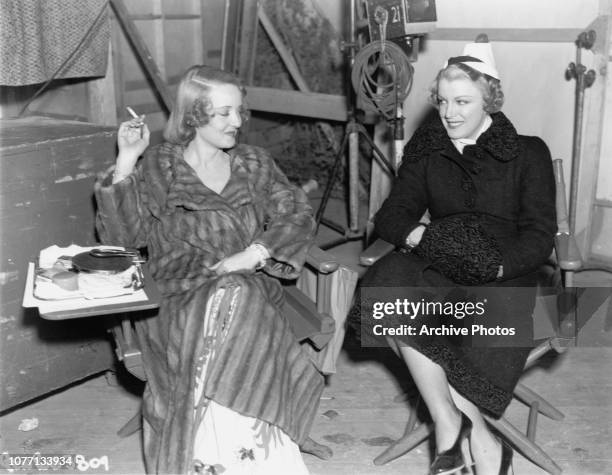 American actress Glenda Farrell visits Bette Davis on the set of the Warner Bros film 'Kid Galahad', 1937. Davis stars in the movie.