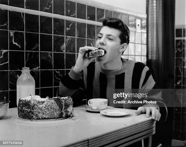 American actor, singer and teen idol Frankie Avalon eats a large slice of cake, circa 1960.