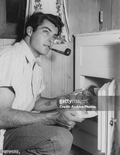 American actor Rory Calhoun gets a snack from the fridge, 30th September 1952.