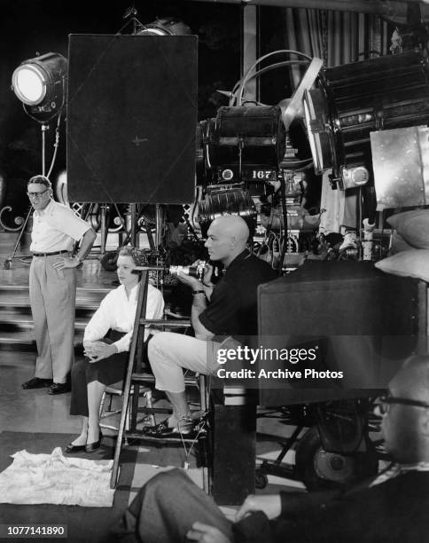 Actor Yul Brynner photographs the set of the 20th Century Fox musical 'The King And I', while co-star Deborah Kerr sits nearby, circa 1956.