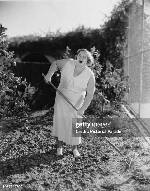 American singer Kate Smith sings while working in the garden, circa 1935.