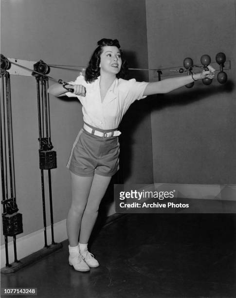 Canadian-American actress Ann Rutherford works out at the MGM studio gymnasium on a pulley machine, circa 1938. She is working on the film 'Dancing...