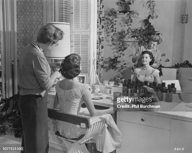 American actress and dancer Cyd Charisse has her hair arranged by MGM stylist Mary Keats in her private dressing room, circa 1955. Charisse designed...