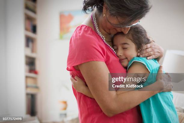 hispanic grandmother and granddaughter hugging - kidstock girl stock pictures, royalty-free photos & images