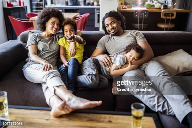 familia afroamericana feliz viendo la tv en la sala de estar. - familia viendo television fotografías e imágenes de stock