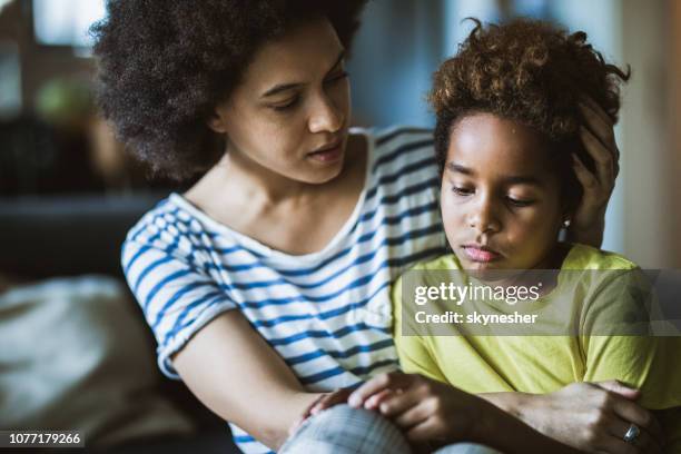afro-amerikaanse moeder troostende haar verdrietig meisje thuis. - depressie verdriet stockfoto's en -beelden
