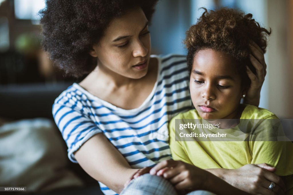 African American mother consoling her sad girl at home.