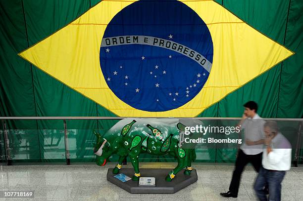 People walk past a cow sculpture inside the JBS SA headquarters building in Sao Paulo, Brazil, on Tuesday, Dec. 21, 2010. Sara Lee Corp.'s talks to...