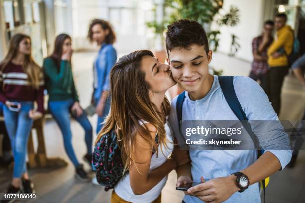 female student kissing her boyfriend in a school hallway. - all about my love stock pictures, royalty-free photos & images