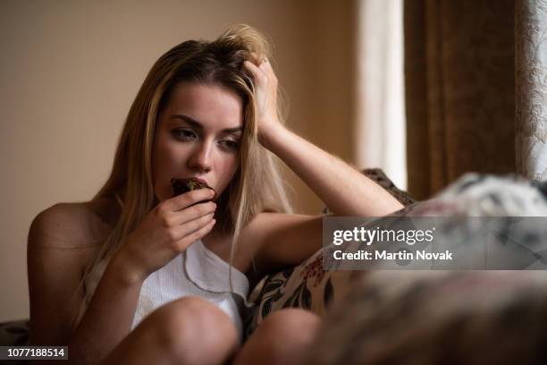 sad young isolated woman eating cupcake - woman chocolate stock pictures, royalty-free photos & images