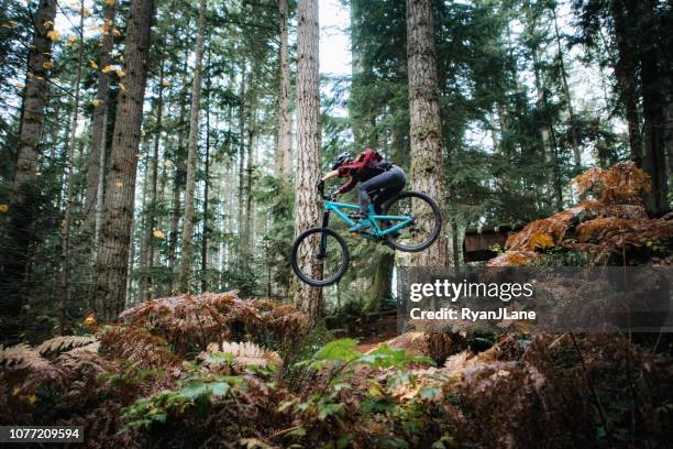 woman mountain biking on forest trails - extreme snowboarding stock pictures, royalty-free photos & images