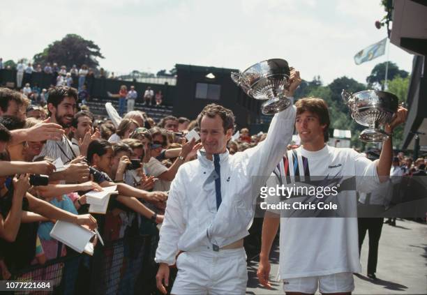 American tennis player John McEnroe and German tennis player Michael Stich lift their trophies after defeating Jim Grabb and Richey Reneberg both of...