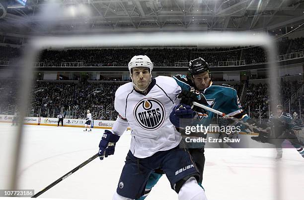 Jean-Francois Jacques of the Edmonton Oilers is hit by Ryane Clowe of the San Jose Sharks at HP Pavilion on December 21, 2010 in San Jose, California.