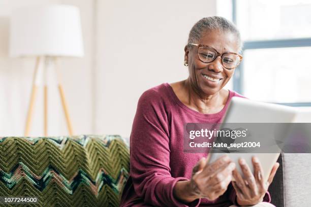senior vrouwen thuis met behulp van tablet pc - huis ter heide stockfoto's en -beelden