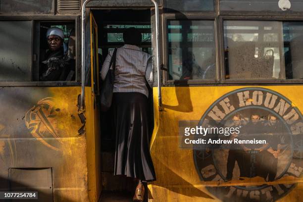 Woman boards a matatu, at a bus stop on December 04, 2018 in Nairobi, Kenya. The private minibuses were to have been banned from the city's central...