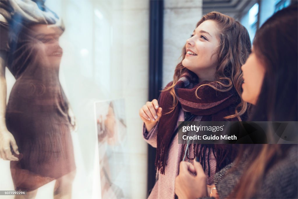 Girlfriends looking into shopping window.