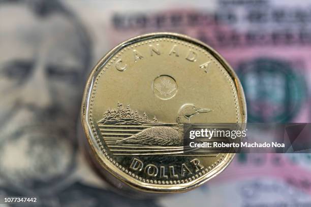 Canadian dollar or loonie over a US 50 dollar bill. Concept of the exchange rate between the two currencies.