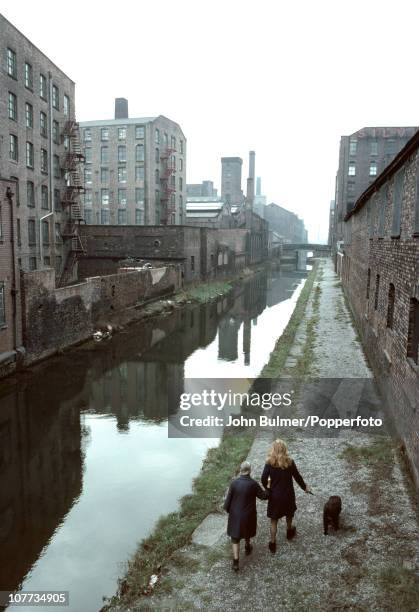 Two women walking a dog by the canal, possibly the Rochdale Canal, in Manchester, England in 1976.