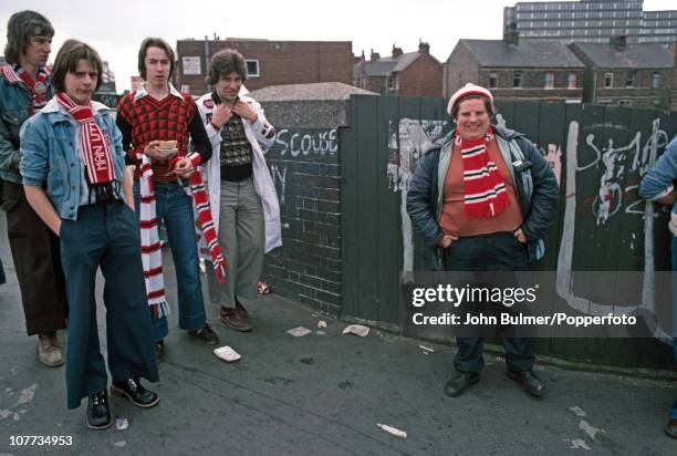 Manchester United fans, one holding a pie, congregate in Manchester prior to a home game in 1976.
