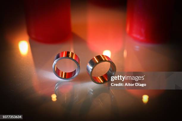 two wedding rings on reflective surface. candle lights - a posh affair stock pictures, royalty-free photos & images