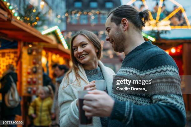 adult couple drinking mulled wine on christmas market in germany - freiburg im breisgau stock pictures, royalty-free photos & images