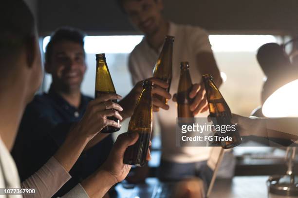 work colleagues toasting with beers in the office, after working late - friday stock pictures, royalty-free photos & images