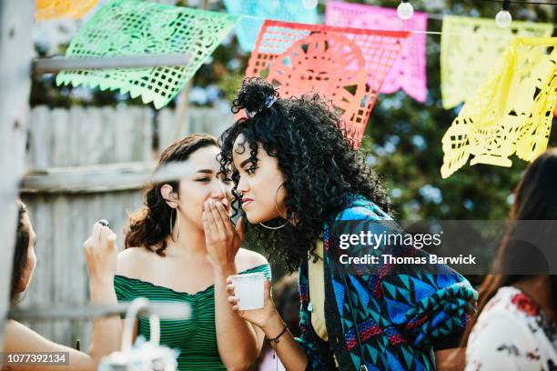 woman whispering to friend during backyard party on summer afternoon - estilo de peinado de sumo fotografías e imágenes de stock