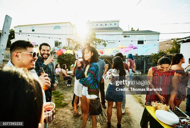 smiling and laughing friends hanging out together during backyard barbecue on summer evening - backyard stock pictures, royalty-free photos & images