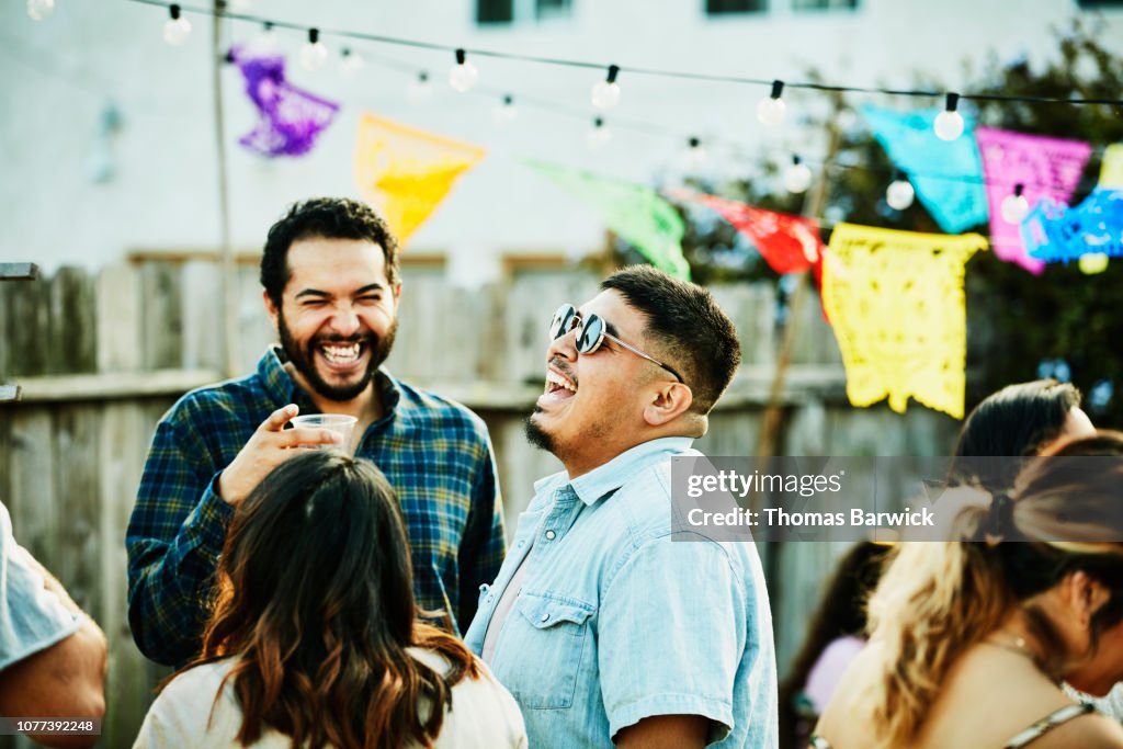 Laughing friends hanging out during backyard barbecue on summer evening