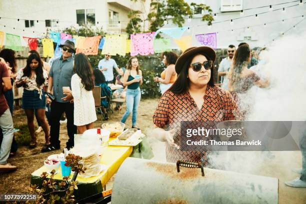 woman cooking for friends at barbecue during backyard party - action cooking fotografías e imágenes de stock