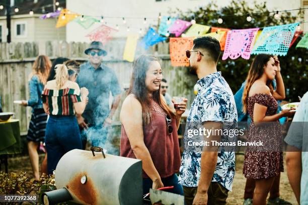 laughing woman in discussion with friend during backyard barbecue on summer evening - backyard barbecue stock-fotos und bilder