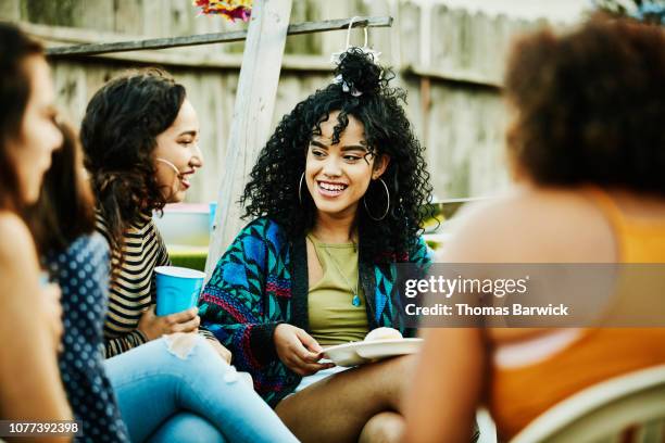 smiling women sharing food and drinks during backyard barbecue - african kids stylish fotografías e imágenes de stock