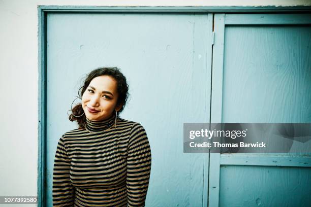 portrait of smiling woman standing against blue wall - latina makeup fotografías e imágenes de stock