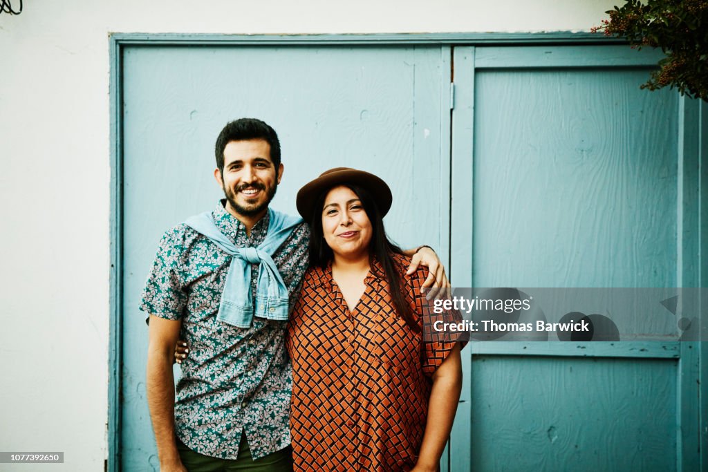 Portrait of embracing couple standing in front of blue wall