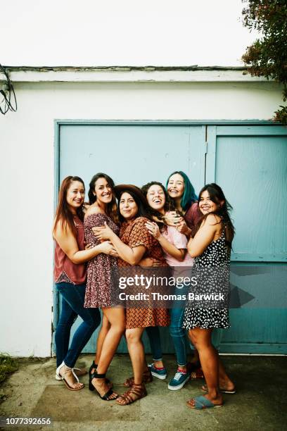 Laughing group of female friends embracing in backyard