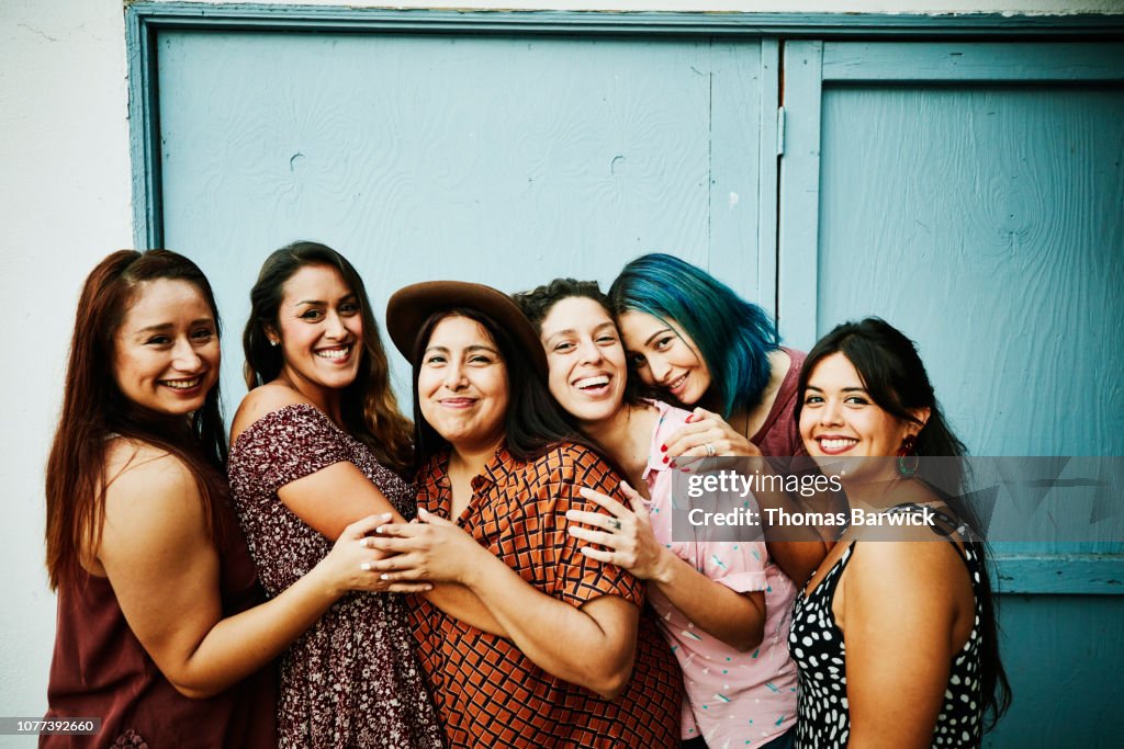 Portrait of female friends embracing in front of blue wall