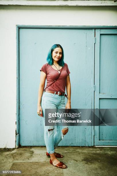 portrait of woman standing in front of blue wall - cinturón azul fotografías e imágenes de stock