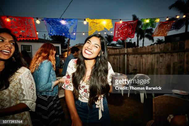 portrait of laughing woman sharing drinks with friends in backyard on summer evening - fiesta fotografías e imágenes de stock