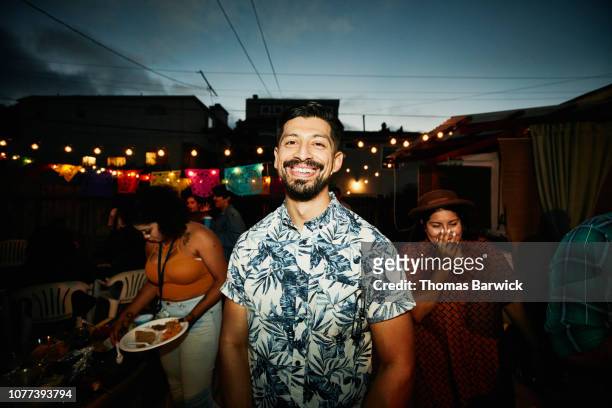 Portrait of smiling man at backyard party with friends on summer evening