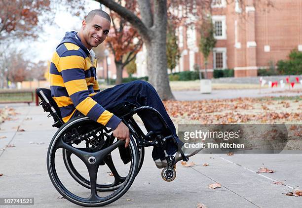 Man doing trick in wheelchair on campus, smiling